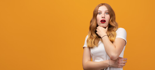 Portrait of the scared girl with wavy redhead, wearing white t-shirt, isolated on yellow background. Copy space