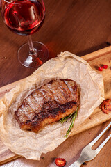 Marbled veal fried on charcoal with vegetables and spices on a wooden board. European cuisine.