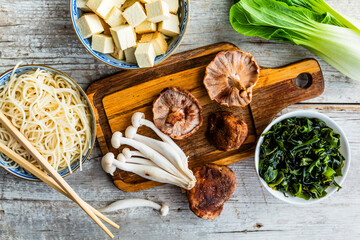 Fresh mushrooms and ingredients for miso soup on a wooden background.