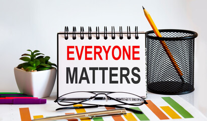 Everyone Matters word with Notepad on white background with markers ,charts and glasses. Business