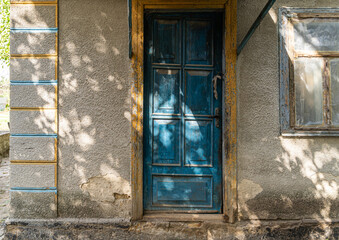 Fototapeta na wymiar Old Ukrainian house and sunlight. Summer day. Blue Door entrance and textured plastered wall. Traditional Ukrainian village countryside style house. atmospheric solar lengths. Summer afternoon