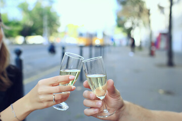 glasses of toast chin chin, hands with glasses of white wine in a street cafe