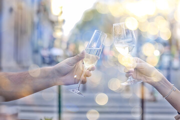 glasses of toast chin chin, hands with glasses of white wine in a street cafe