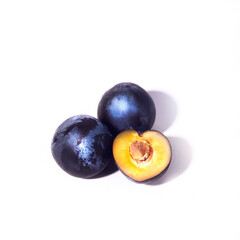 Three plums on a white background. A half of a plum with a stone. Close-up top view. Flyer, booklet.
