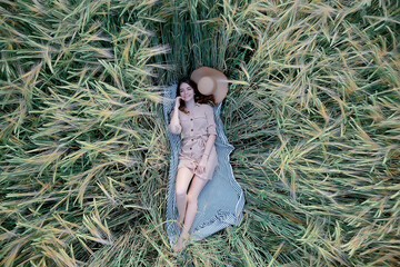 girl lies in a wheat field top view / summer vacation relaxation freedom, picnic in nature view from a copter