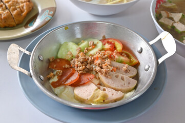 Breakfast with fried egg in a pan top with mince pork and local sausages - Thai northeastern style food