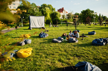 Young multi ethnic group of people watching movie at poof in open air cinema.