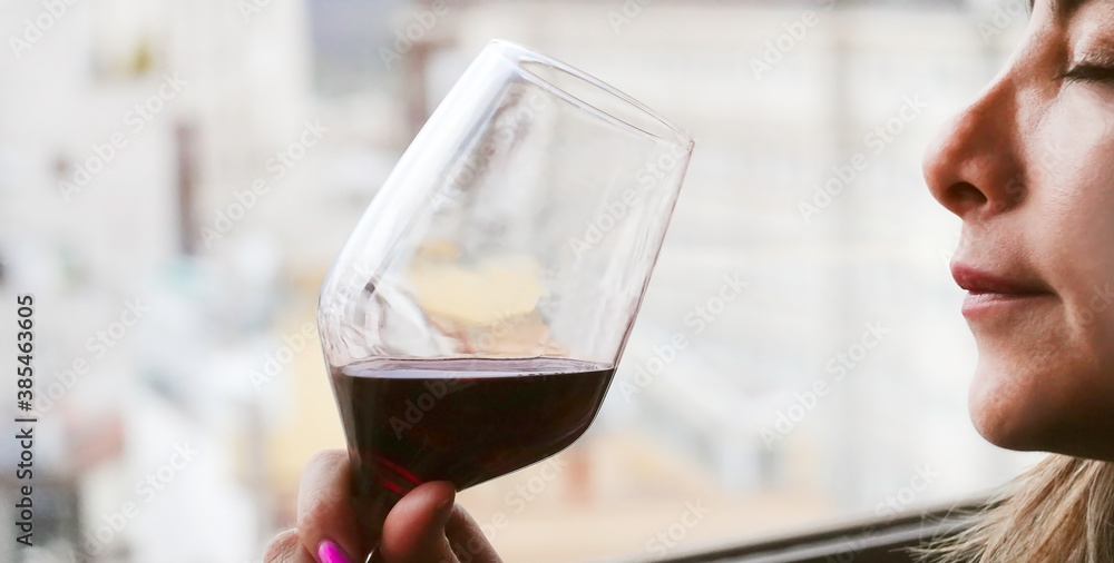 Wall mural happy moment of woman standing in her apartment sipping a glass of red wine with her eyes closed in 