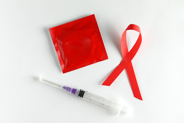 Red ribbon, syringe and condom on white background. World AIDS Day.