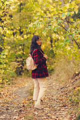 smiling girl in autumn stands on forest road and looks at the camera