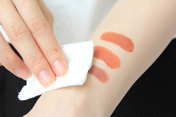 Closeup of hands of woman makeup artist testing lip gloss different colors on her hand