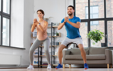 sport, fitness, lifestyle and people concept - smiling man and woman exercising and doing squats at...
