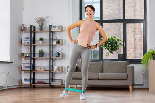 sport, fitness, lifestyle and people concept - happy woman exercising with resistance band at home