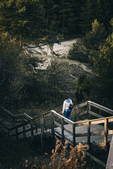 A beautiful vertical image of young female goes down the wooden stairs in a deep forest.