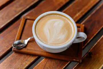 White cup with Coffee latte on wooden table in coffee shop viewed from top