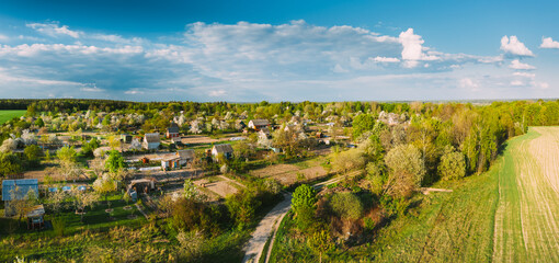 Fototapeta na wymiar Countryside Rural Landscape With Small Village, Gardens And Green Field In Spring Summer Day. Elevated View. Panorama
