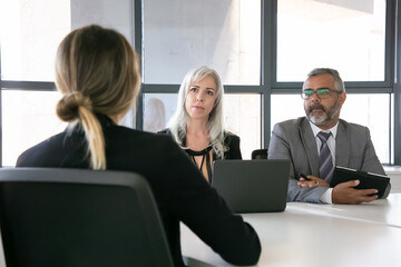 Serious employer and HR manager talking to job candidate at interview. Back view, closeup. Human...