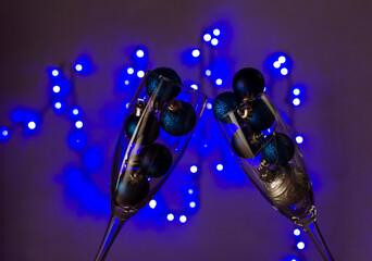 Fototapeta na wymiar Closeup of glasses full of Christmas bulbs against blue garland lights on the wall.