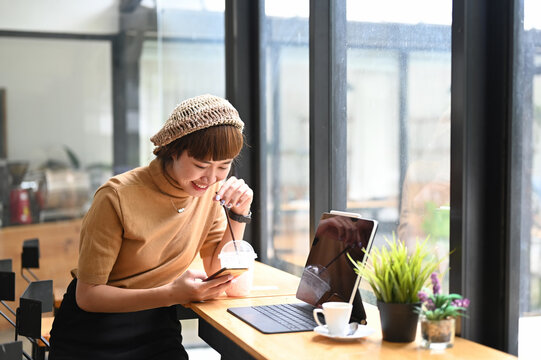 Shot of young female using smartphone atn her workstation.