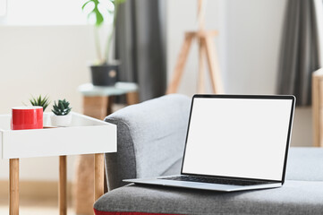 Mockup blank screen laptop on couch in living room. For graphic display montage.