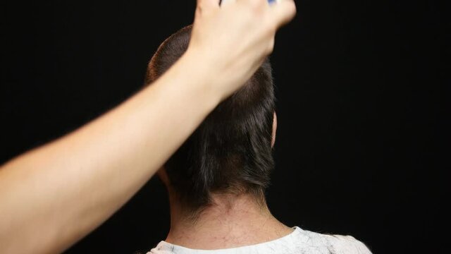 Shot of the back of the head of a brunette male getting a buzz cut.