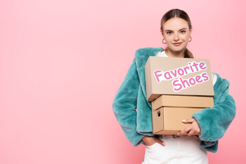 Fototapeta na wymiar pleased woman in sunglasses holding boxes with favorite shoes lettering on pink, black friday concept