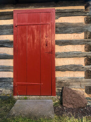 Red wooden door with long, old style hinges In an early American log cabin on the Daniel Boone...