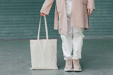 Woman in coat with white cotton bag in her hands. Mockup and zero waste concept.
