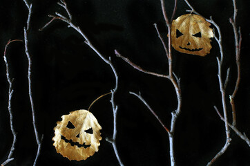 Autumn leaves curved like Halloween pumpkins, naked branches. Halloween backgrouns.