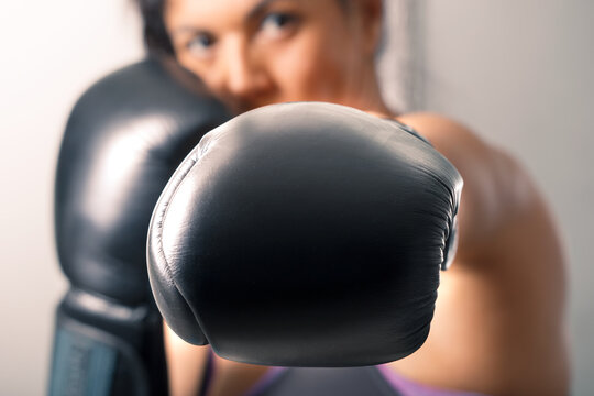 A brunette girl learns fighting techniques of self-defense in boxing gloves.