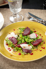Salad with roasted beetroot, pine nuts, soft goat cheese on the table at restaurant