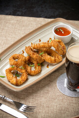 Deep fried squid with tomato sauce and glass of beer on the table at restaurant