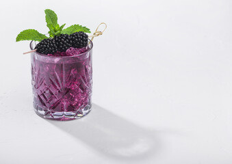 Fototapeta na wymiar Glass of refreshing summer cocktail with blackberry, ice and mint on white background. Soda and alcohol mix.