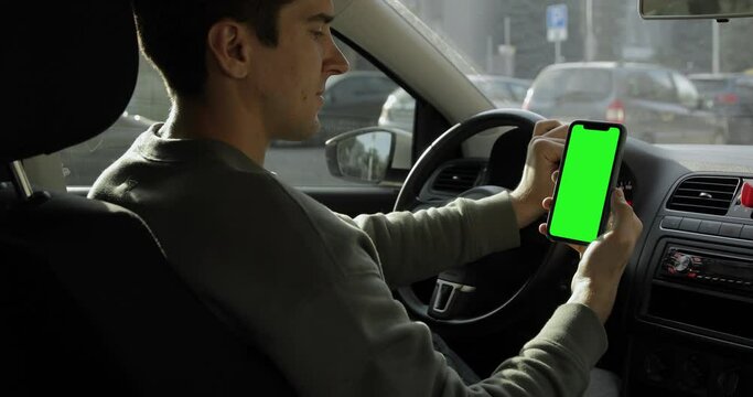 Driver using a smartphone inside the car. Chromakey iPhone 11 Pro Max with green screen. Internet society, hipster freelancer searching for the best route.