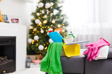 Cleaning before Christmas. Multicolored cleaning supplies. Sponges, rags and spray with festive decorations against modern home background