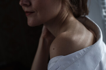 Naklejka premium Sensual close up portrait of beautiful young lady relaxing at the window. female shoulder close up. hard shadows