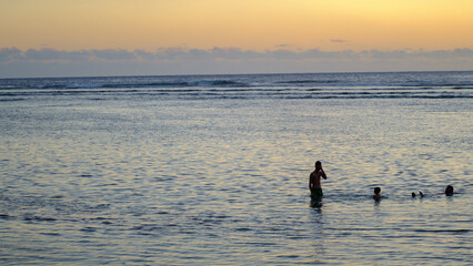 People bathing and swimming at the sunset in the Indian Ocean