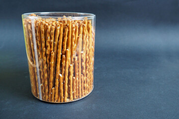 brown straight salted pretzels in plastic transparent packaging on a black background side view