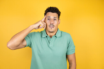 Young handsome man wearing green casual t-shirt over isolated yellow background smiling and...