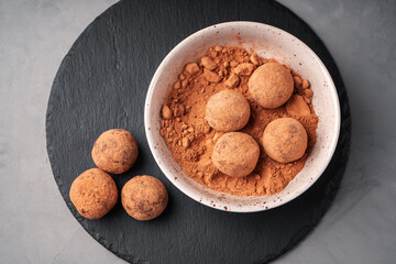 Date candy balls in a plate with carob on a slate Board top view