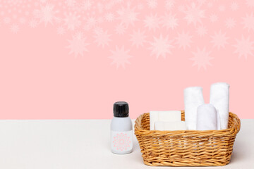 Basket with bath accessories such as soap bars, Cream and cosmetic tissues for body care on a white table over pink background with copy space. For your product display montage.