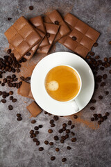 cup of black coffee chocolate bar and coffee beans.