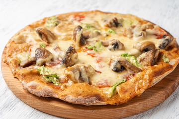 Vegetarian pizza with mushrooms on wholegrain flour dough on a wooden Board close-up