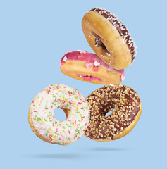 Mix of flying multicolored sweet donuts with sprinkles on blue background