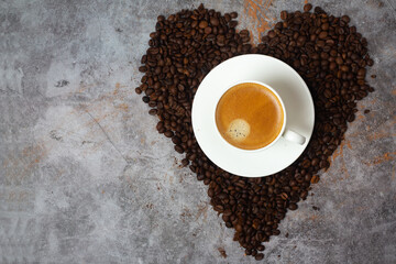 a cup of coffee in a heart made of coffee beans on a gray background and a place for the text.