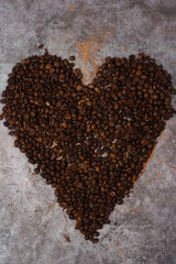 heart made of coffee beans on a gray background.