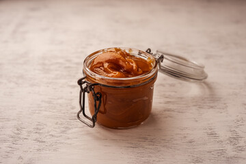 Thick buckwheat honey in an open glass jar with a lid on a loop