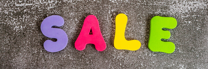 Word SALE written in bright colorful letters on black background. Banner.