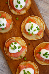 Homemade Blini with Smoked Salmon, Creme and Chives on a rustic wooden board, overhead view. Flat lay, top view, from above.