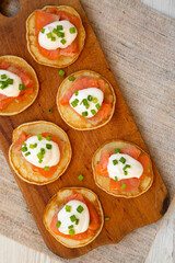 Homemade Blini with Smoked Salmon, Creme and Chives on a rustic wooden board, view from above. Copy space.